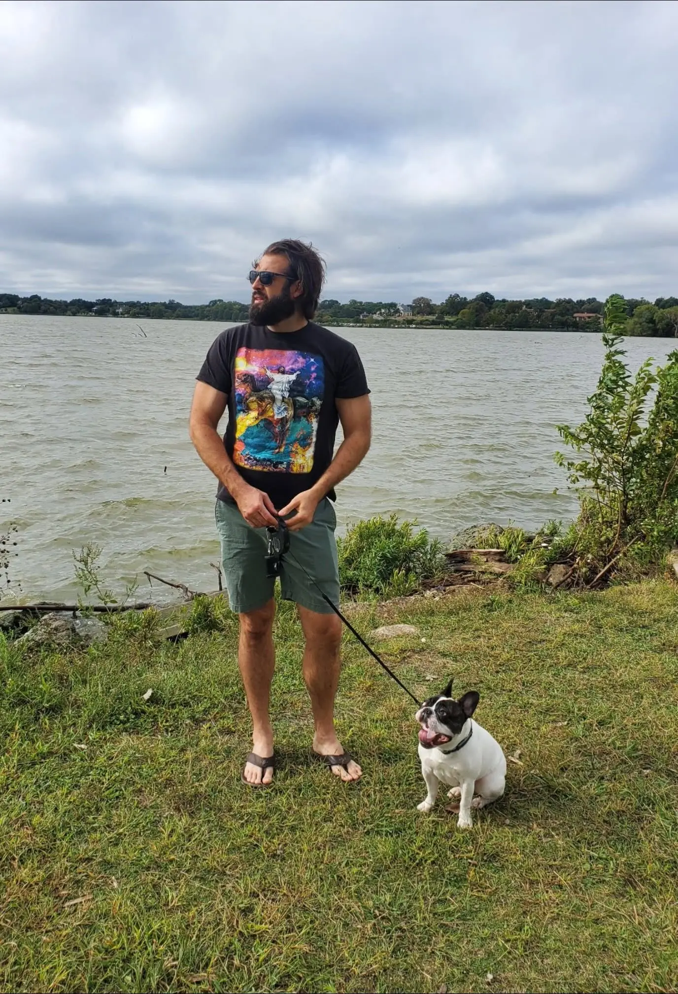 Mitch standing by a lake with his French bulldog on a leash
