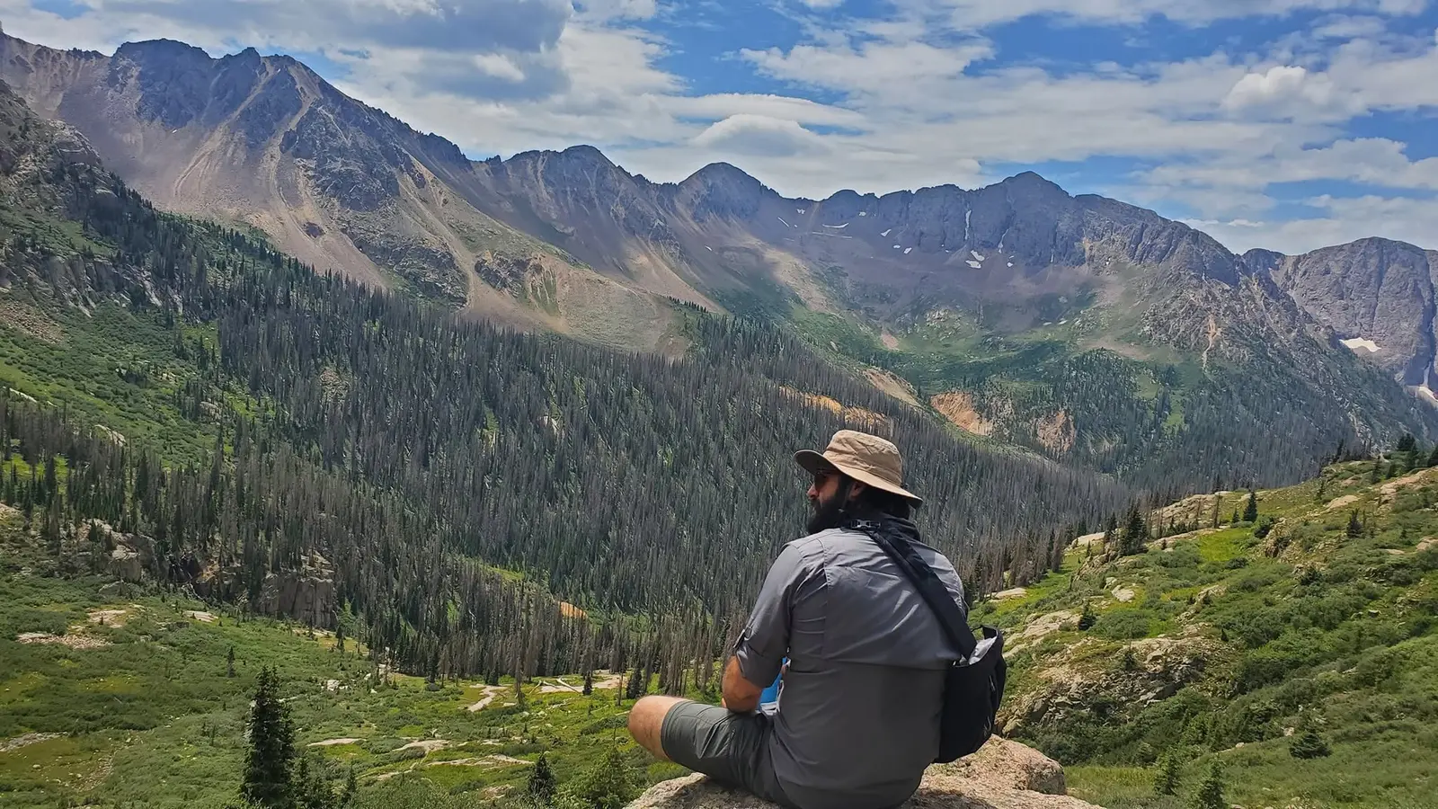 Mitch sitting in a sun hat, looking out over a mountain range