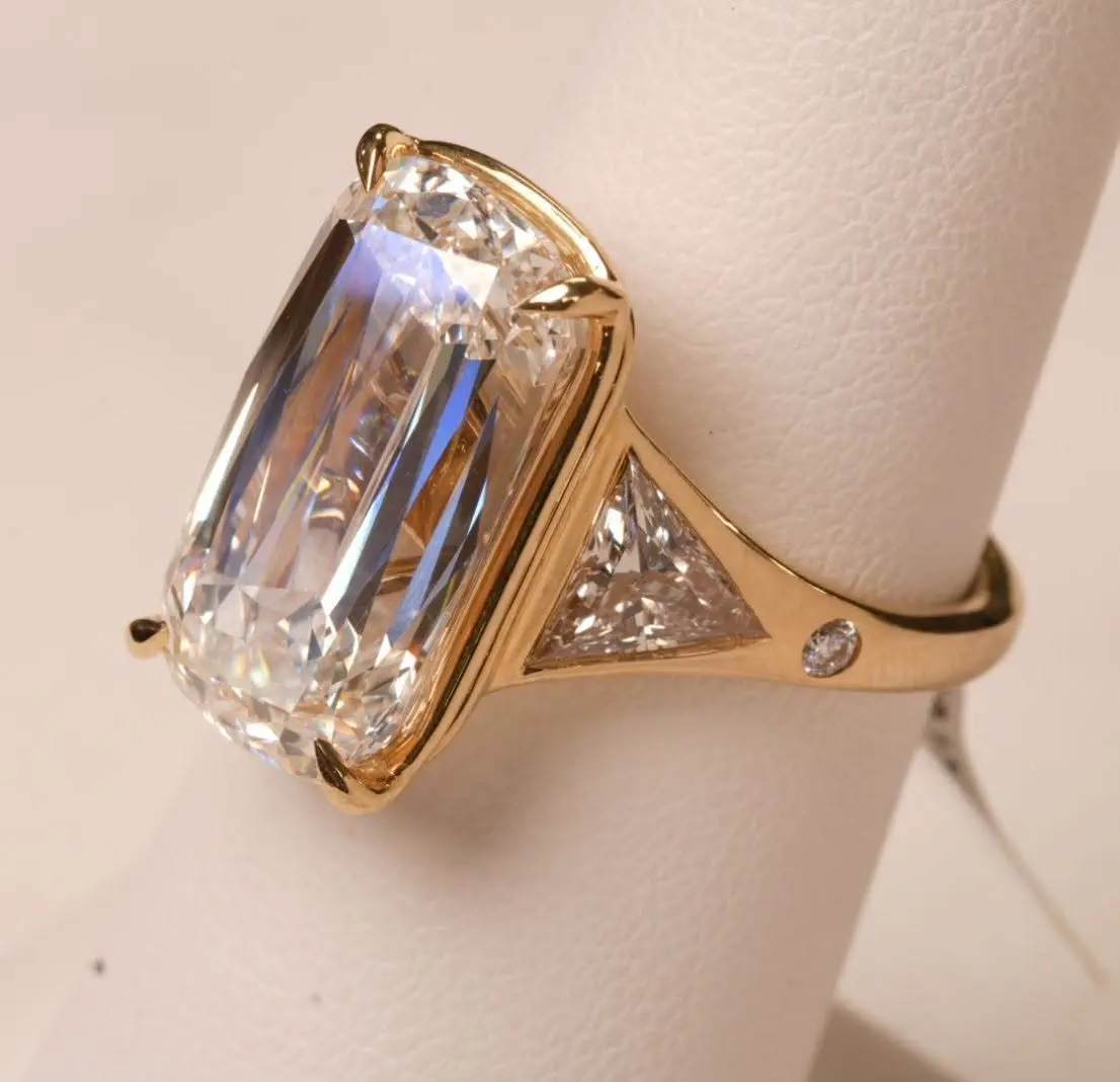 Close-up of an elongated cushion-cut diamond ring with trillion side stones in yellow gold