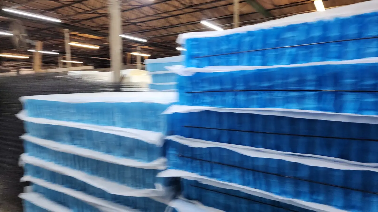 Stacks of blue-wrapped mattress spring units on the Golden Mattress Company factory floor in Dallas