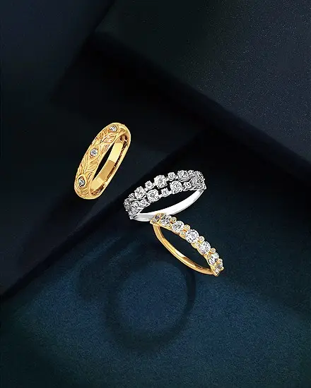 A patterned yellow gold band and a diamond eternity band resting on dark blue velvet
