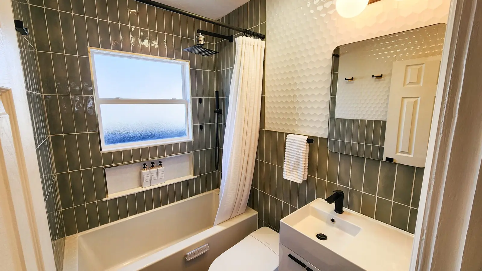 The new bathroom at The Elati House with green tile and a floating vanity