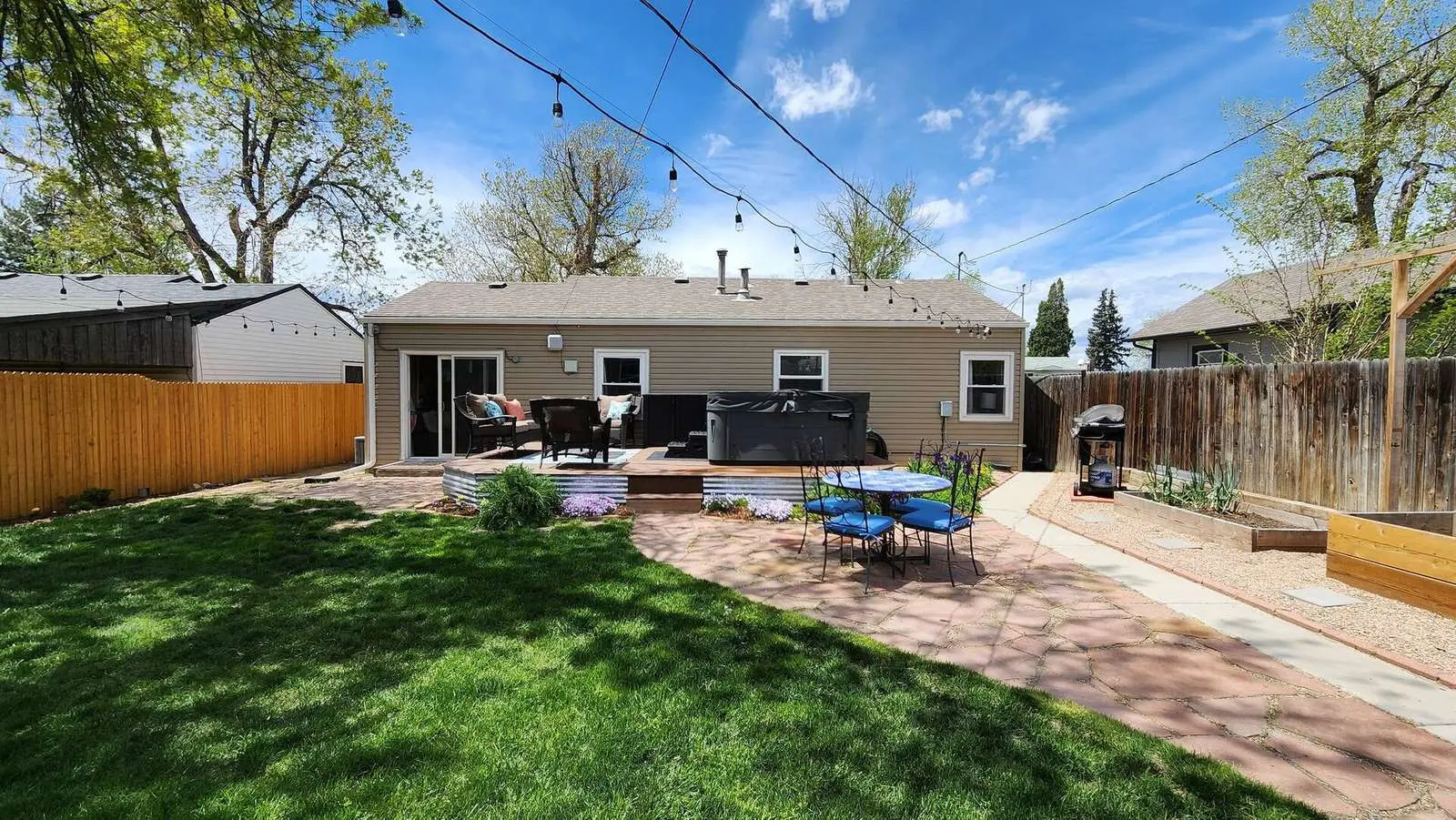 Backyard of The Elati House near Denver: a green lawn, string lights, a patio and the back of the house