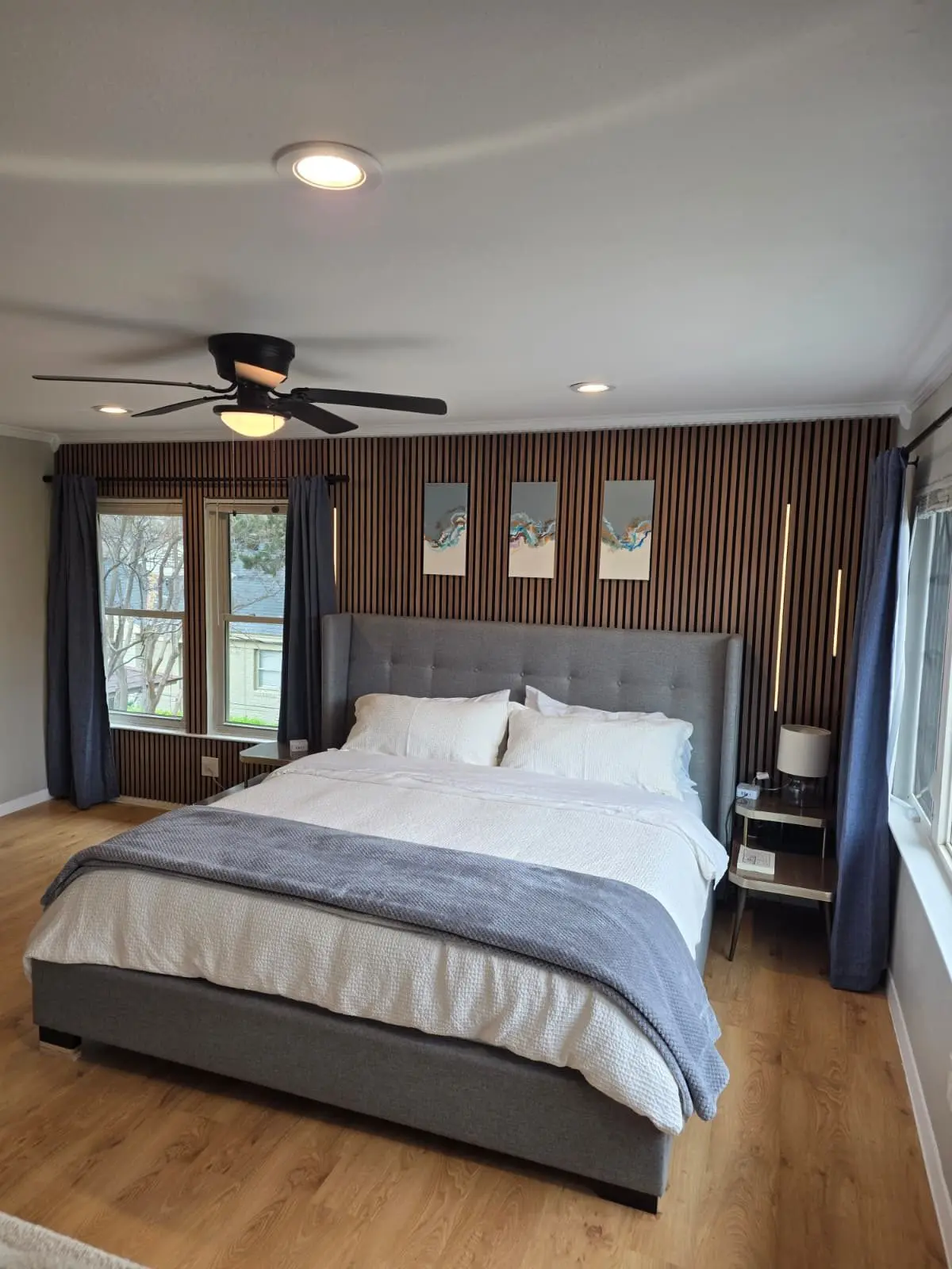 The king bed at The McCosh Apartment under a ceiling fan, with wood floors