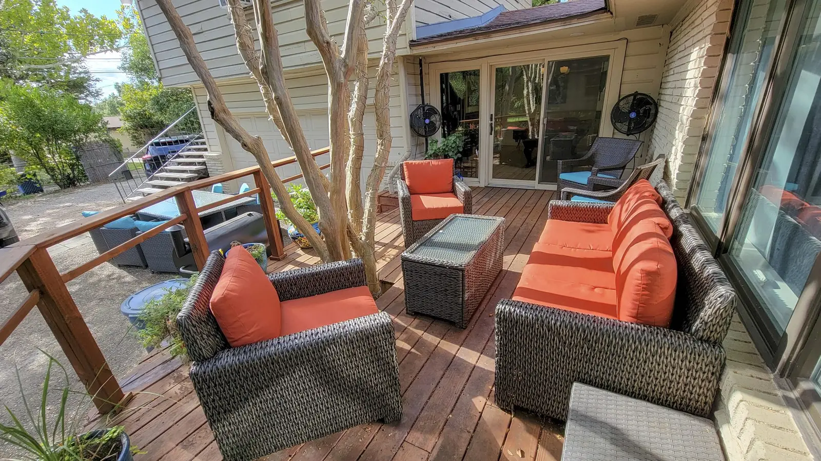 The furnished back deck at The McCosh House with orange cushions under the trees