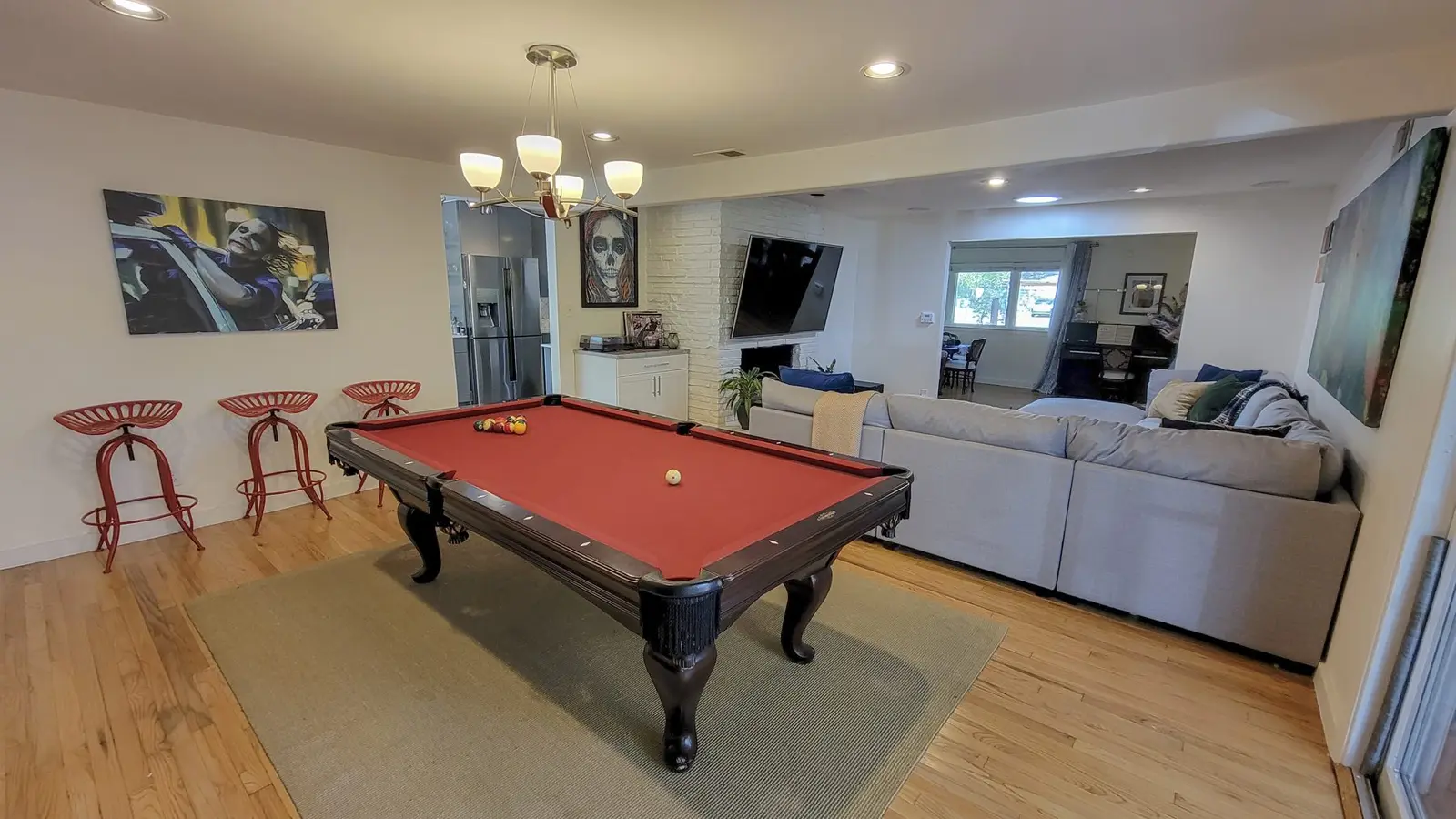 The pool table at The McCosh House under a chandelier, with the living room behind