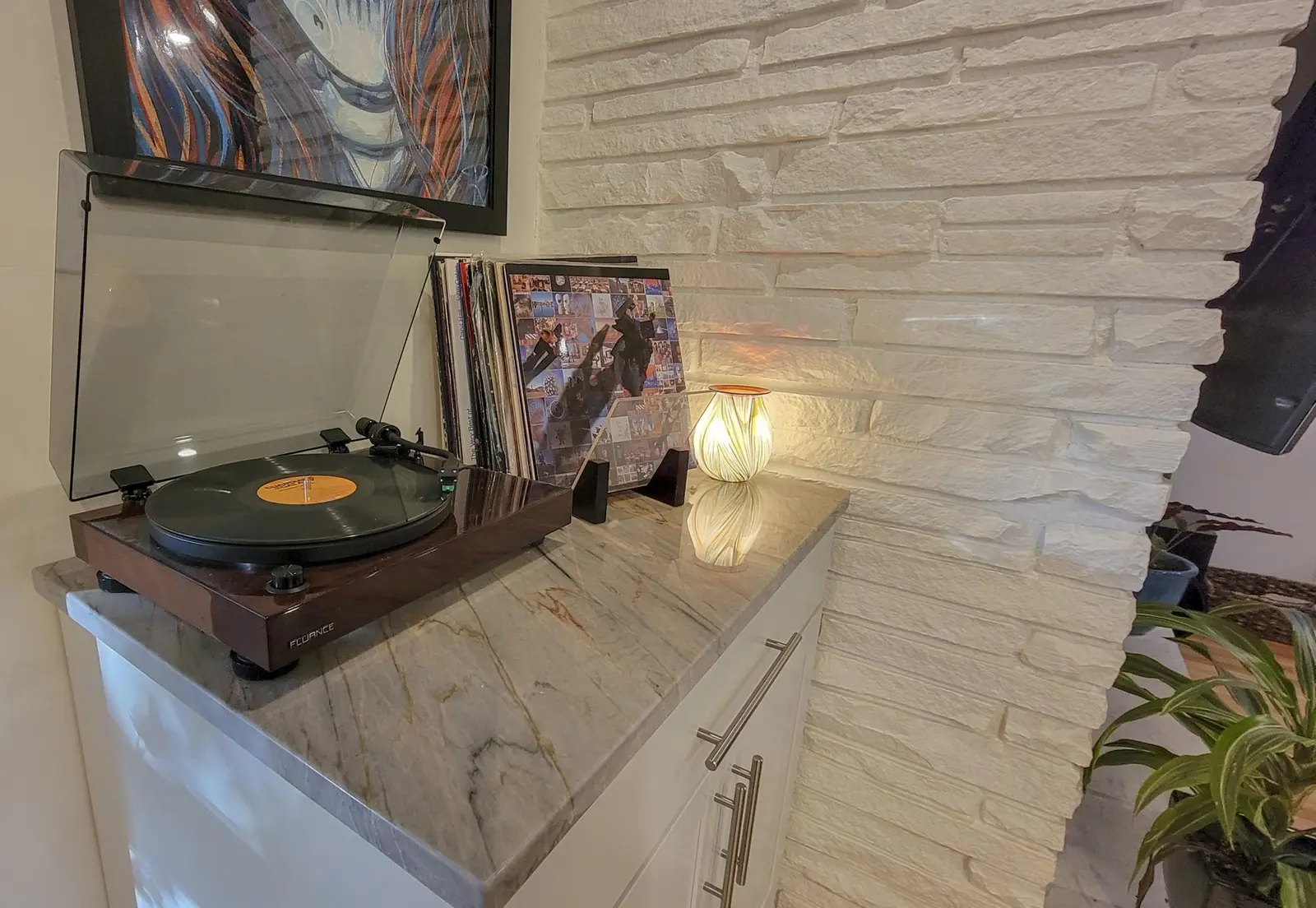 A record player and a stack of records on a stone-wall shelf at The McCosh House